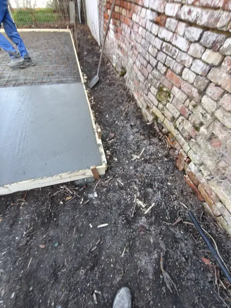 A friss beton a téglafal mellett, terítés közben.