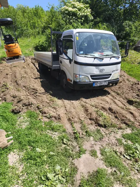 Rakodás a billenőplatós teherautóra a kiszedett sávban.